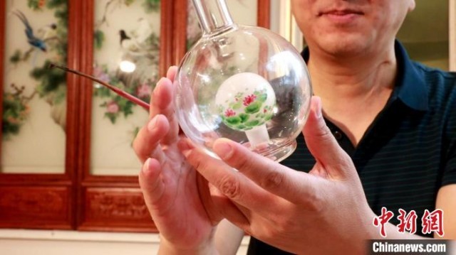 图为正在检查内画酒壶着色情况。　赵奇 摄