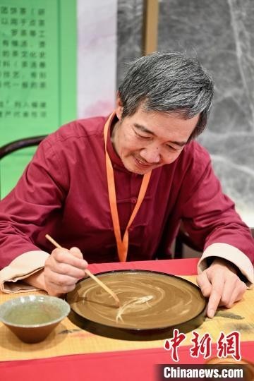图为老艺人现场制作“茶百戏”，该“非遗”是一种使茶汤的纹脉形成物象的古代茶艺。　王东明 摄