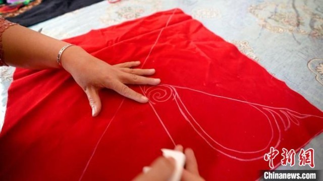 哈丽玛西·阿黑特在布料上手工画哈萨克族刺绣的图案。　戎睿 摄