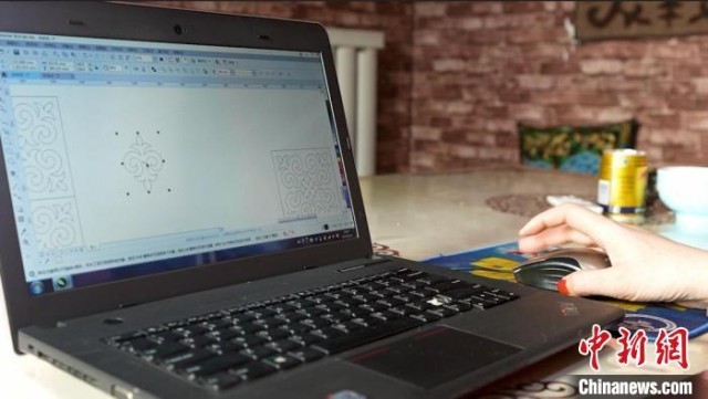 布丽恒·哈布拉哈提在电脑上设计哈萨克族刺绣的图案。　左丹丹 摄
