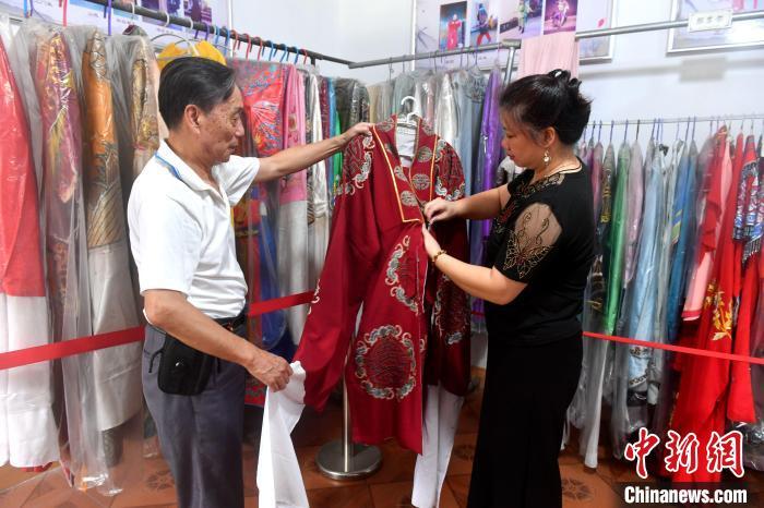 欧成斌(左)和徒弟谢金钗正在整理演出服装。 吕明 摄 欧成斌(左)和徒弟谢金钗正在整理演出服装。 吕明 摄