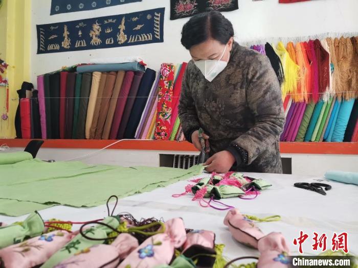 图为甘肃庆阳香包传承人刘兰芳裁剪布料,用于制作防疫“平安香包”。 甘肃省非物质文化遗产保护中心 摄 图为甘肃庆阳香包传承人刘兰芳裁剪布料,用于制作防疫“平安香包”。 甘肃省非物质文化遗产保护中心 摄